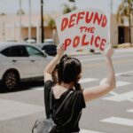 woman holding defund the police banner