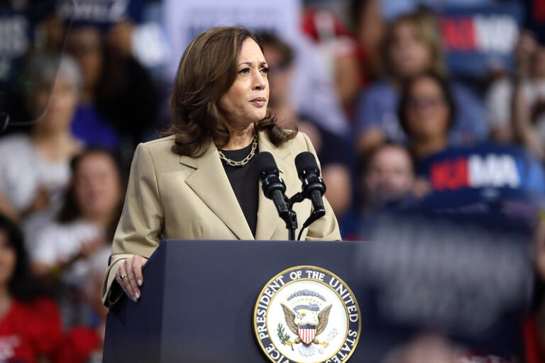 Kamala Harris, a historic figure as the first Black woman vice-presidential nominee for a major party, speaks at a podium.